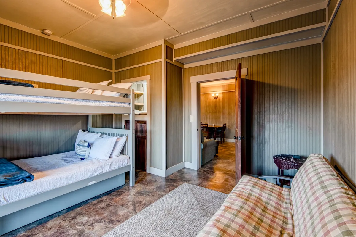 A welcoming bunk room featuring multiple bunk beds and a cozy sofa. The room is designed for group or family stays, with a layout that encourages both relaxation and shared moments.