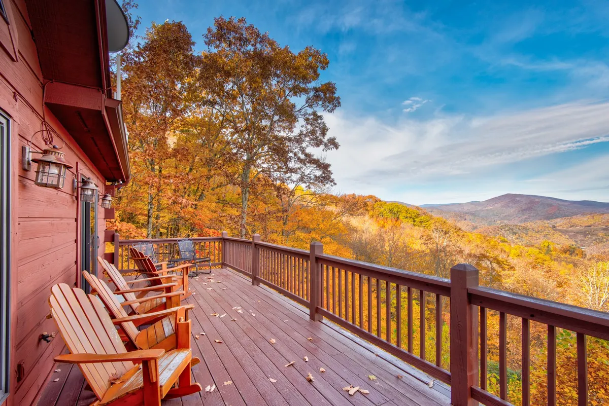A scenic wooden deck stretches out with classic Adirondack chairs perfectly positioned to soak in sweeping mountain views and autumn foliage. The space beckons guests to relax, gather, and savor the outdoors just steps away from the interior retreat.